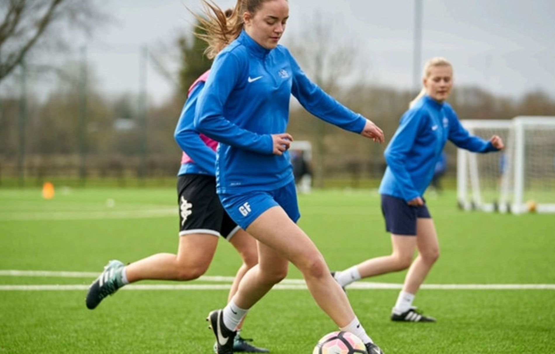 Mädchen in blauem Nike Langarmshirt auf dem Fußballplatz