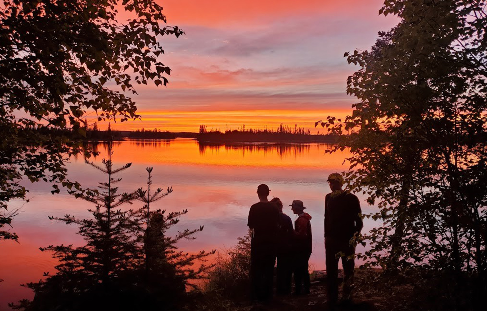 4 Personen bei Sonnenuntergang an einem See.
