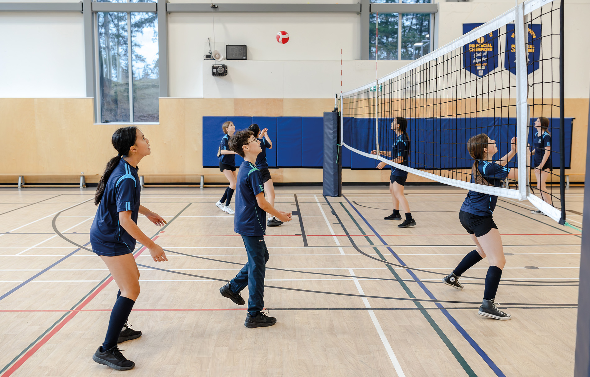 Schüler die Volleyball in einer Halle spielen.