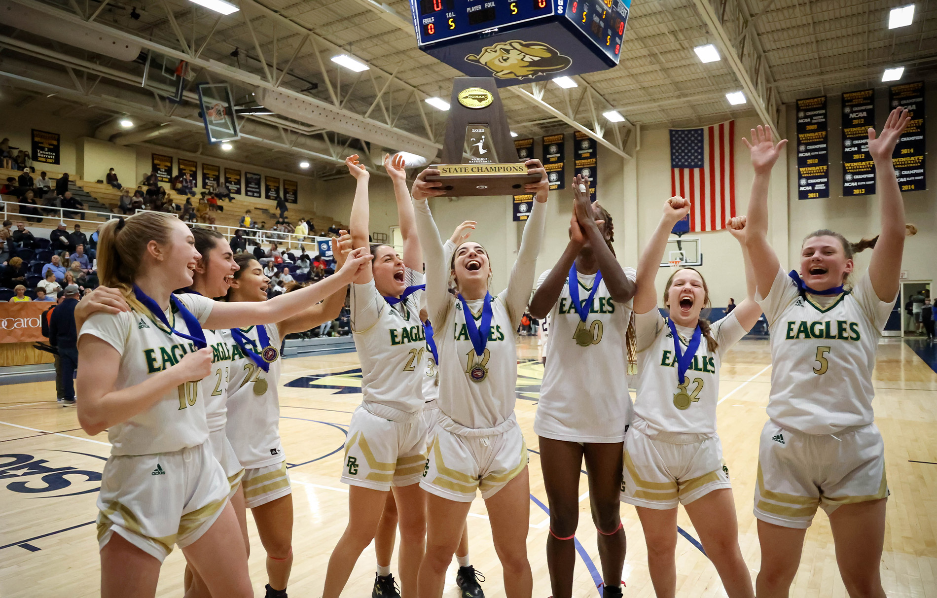 Frauen im Basketballtriktot die einen Pokal in die Luft heben und jubeln