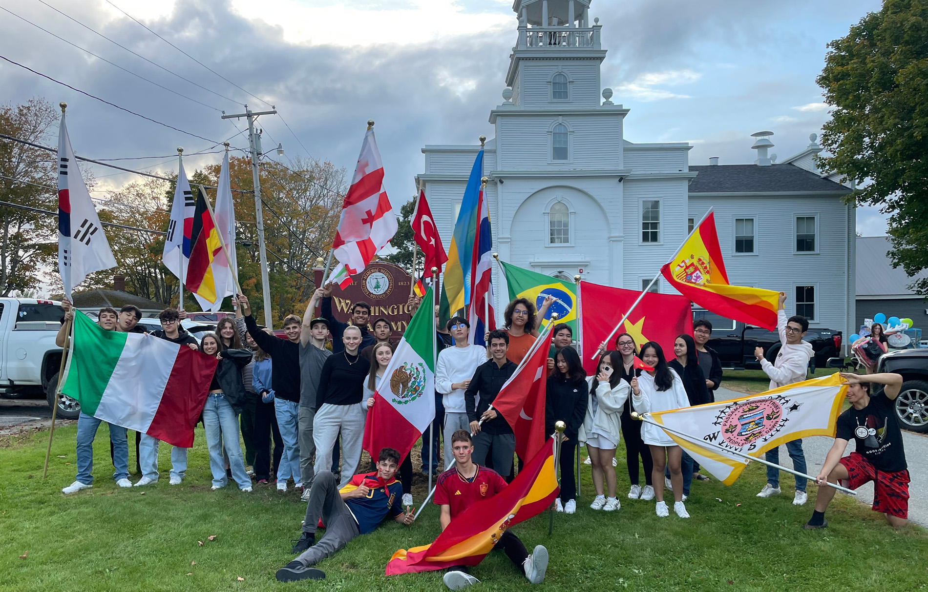 Schüler mit verschiedenen Länderfahnen vor einem weißen kirchenähnlichen Gebäude