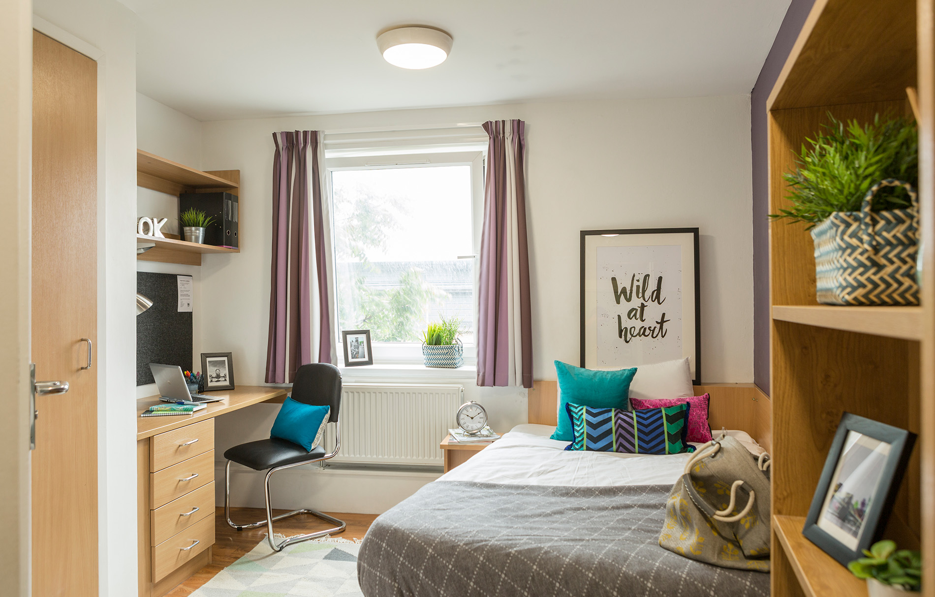 Gut ausgestattetes und helles Zimmer mit einem Bett und einem Schreibtisch 