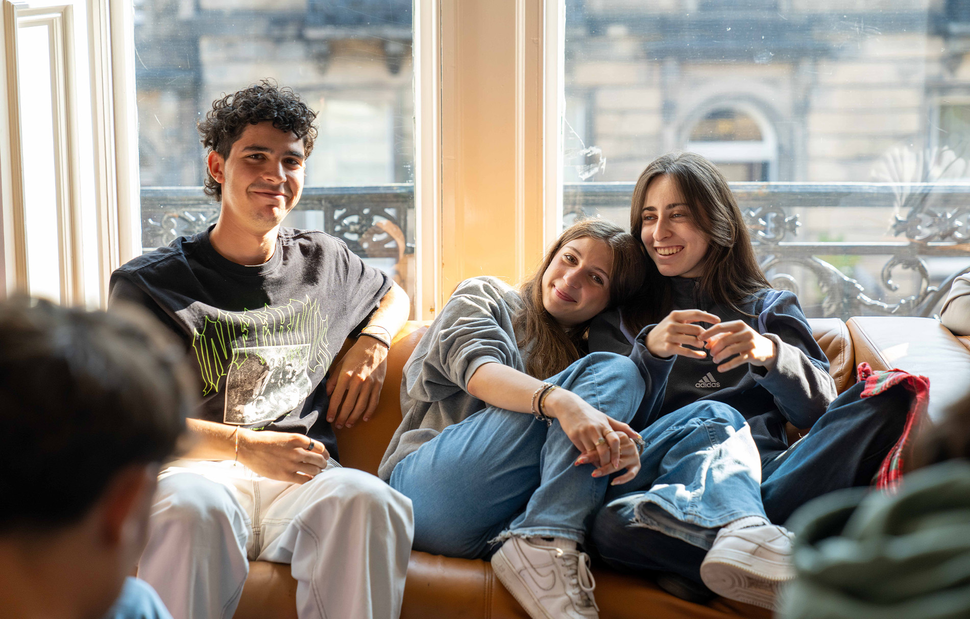 Schüler sitzen auf einem Sofa und lachen in die Kamera