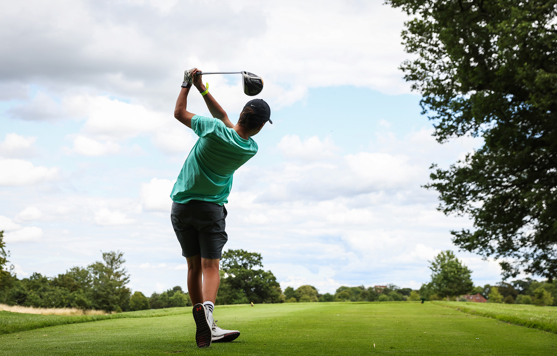 Junge auf dem Golfplatz, der den Ball abgeschlagen hat