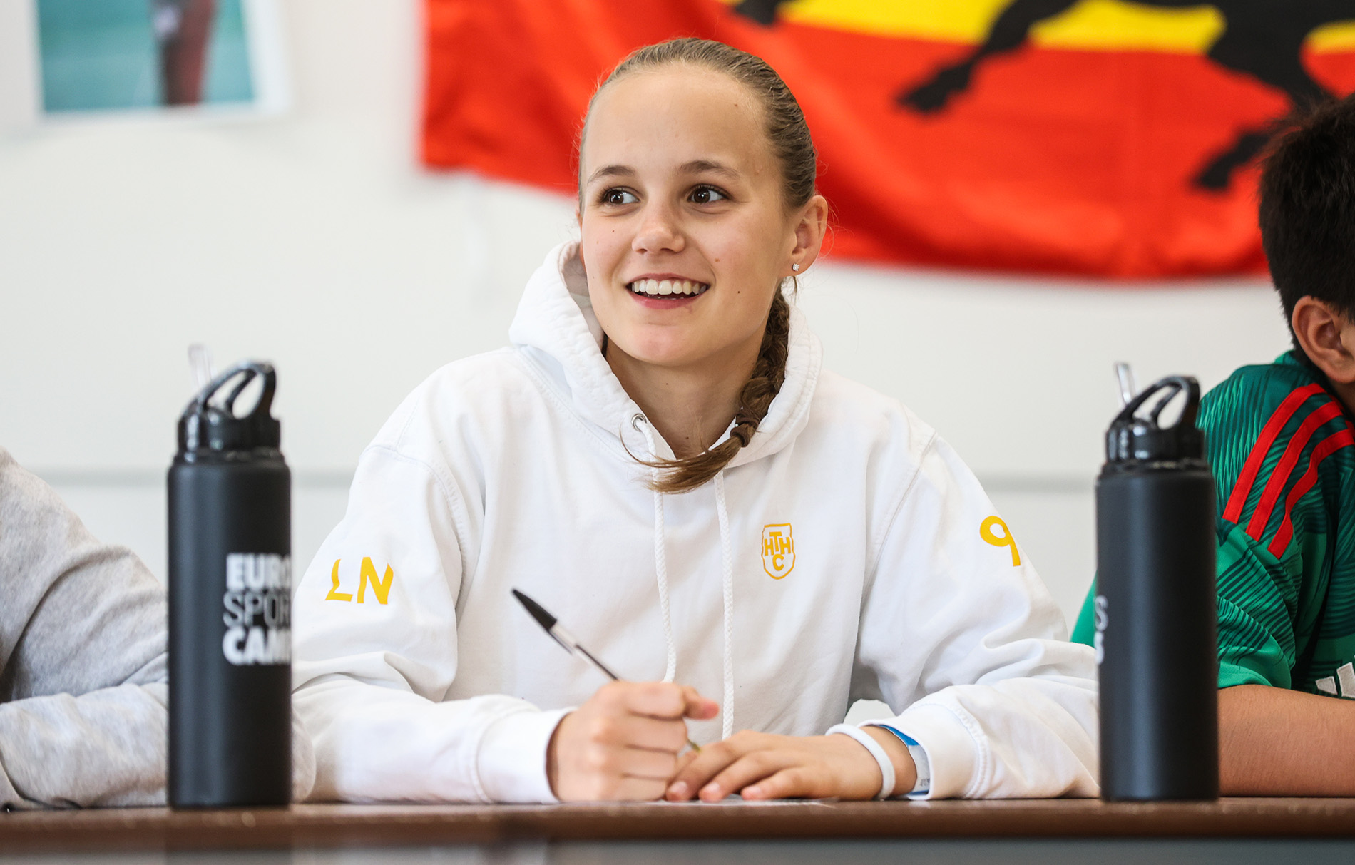 Mädchen mit weißem Hoodie und Kugelschreiber in der Hand