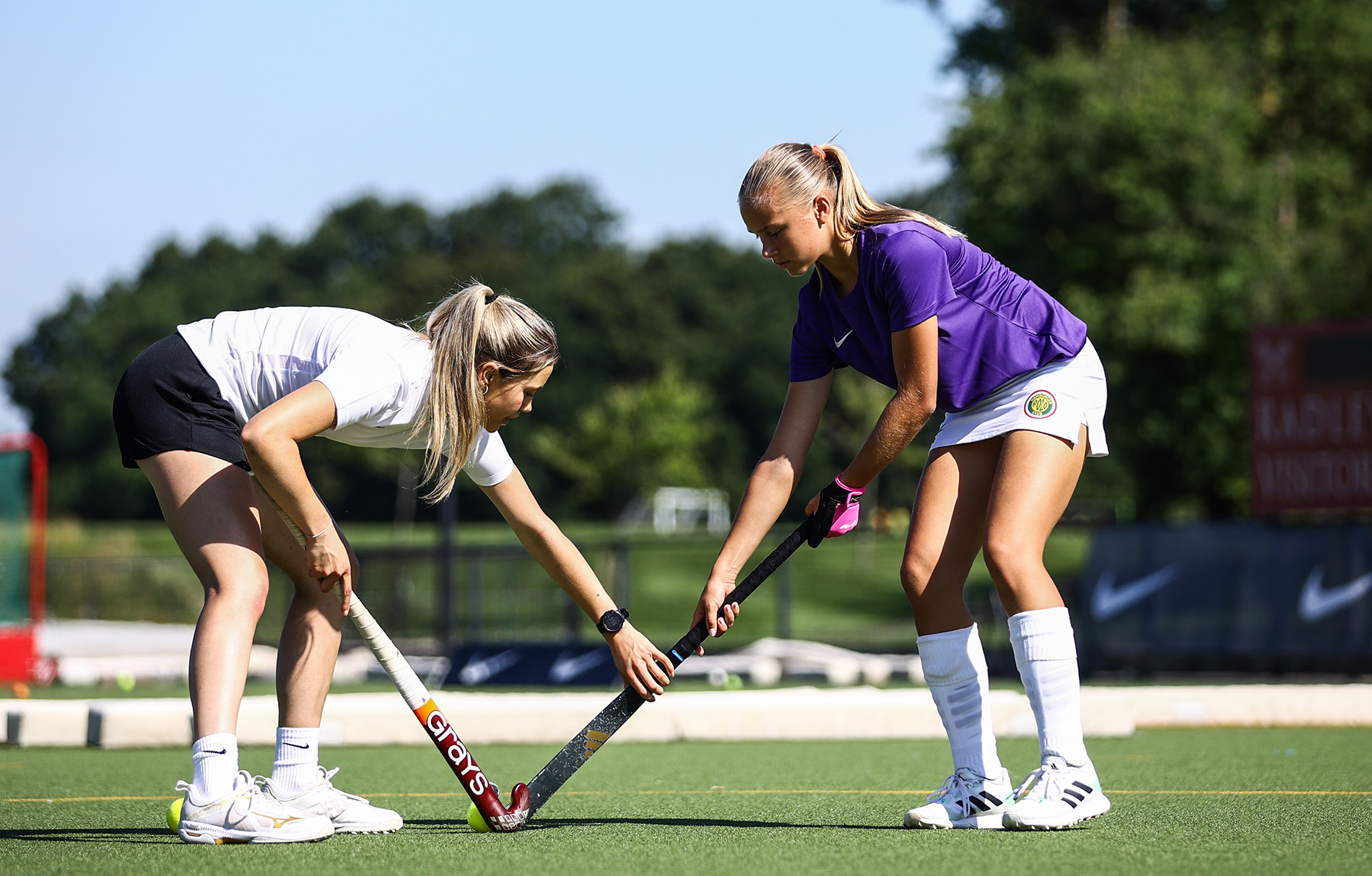 Zwei Mädchen auf dem Hockeyfeld, die die Schlägerposition ausrichten