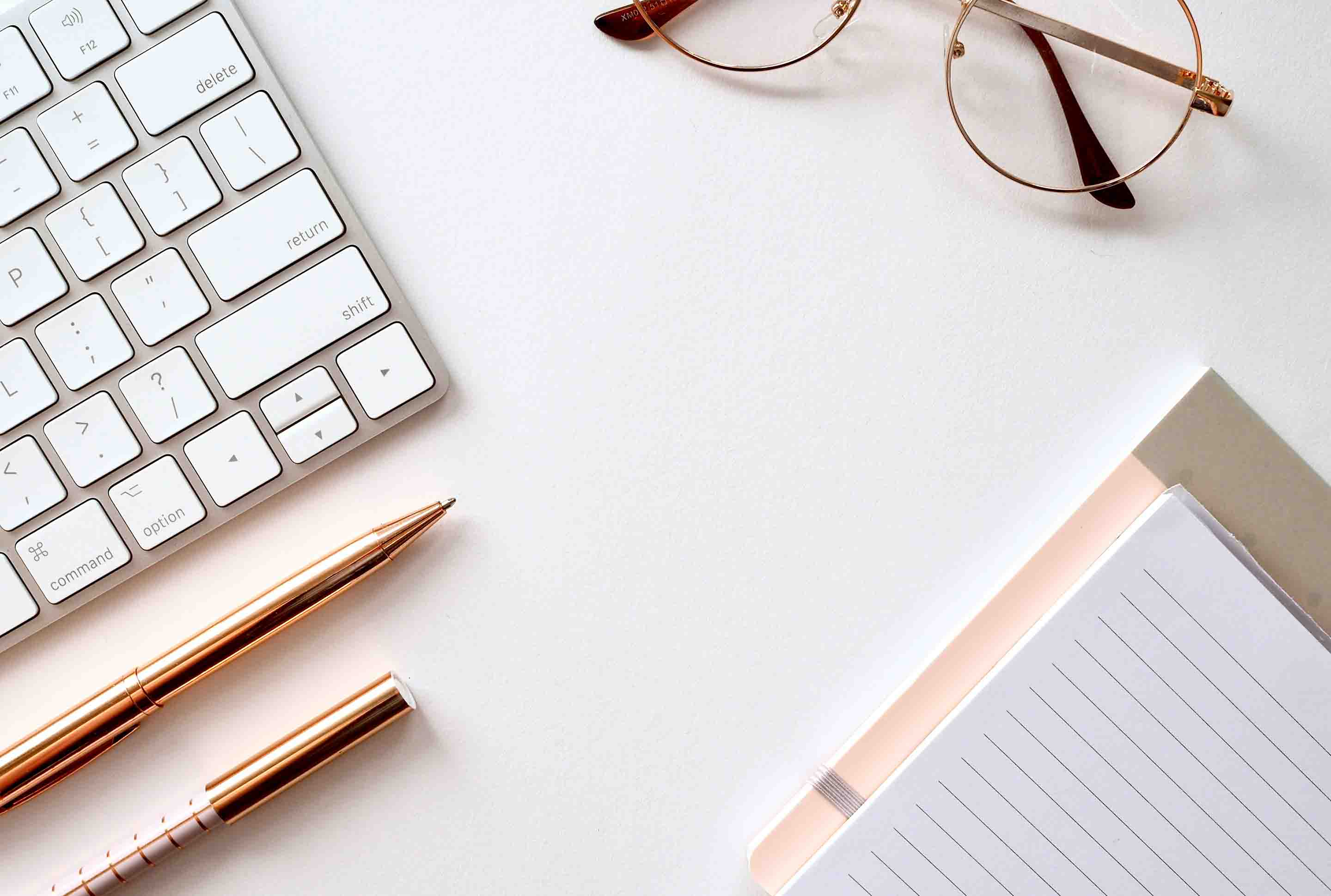Schreibtisch mit Tastatur, Brille, Block und Stiften