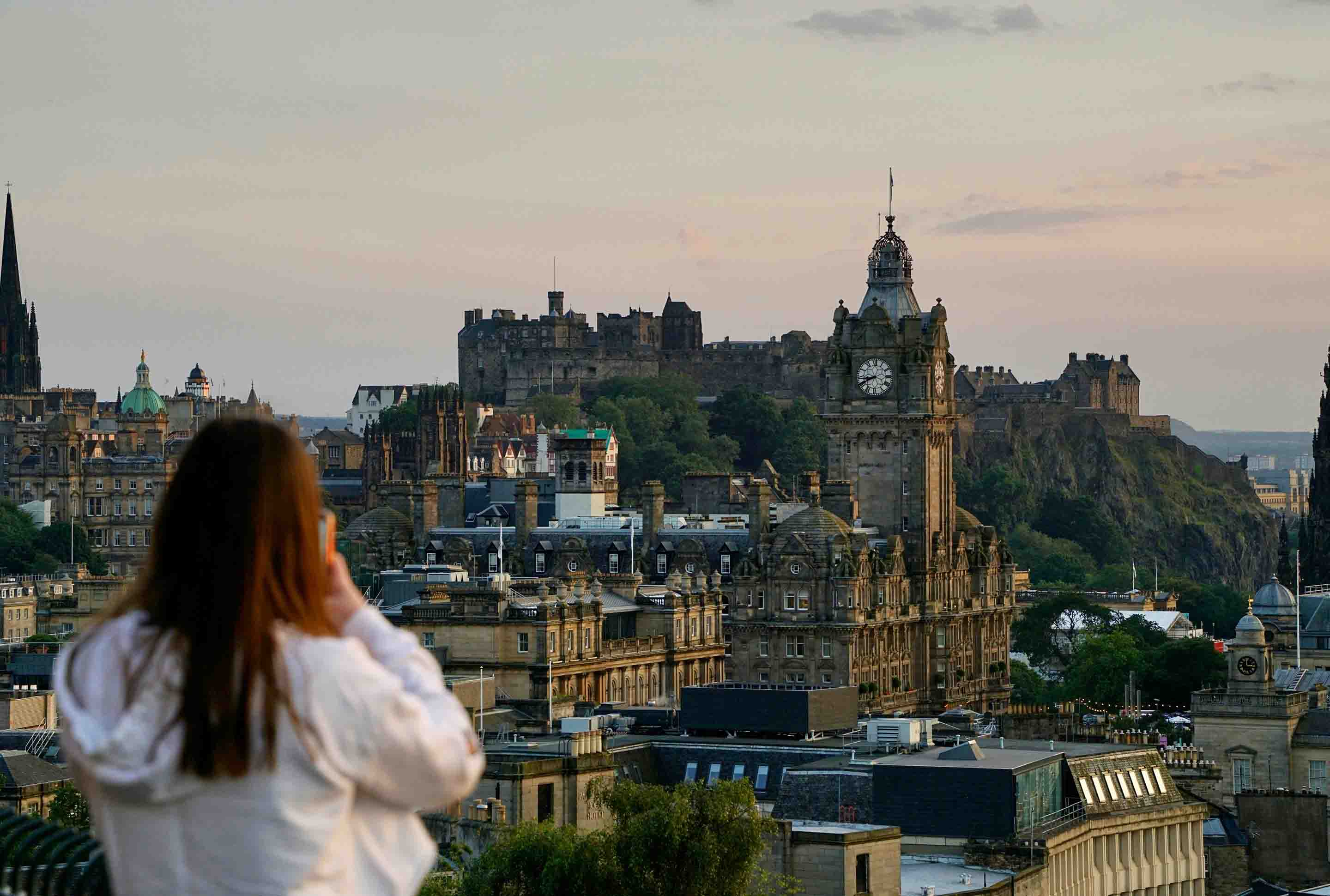 eine junge Frau fotografiert die Aussicht auf Edinburgh